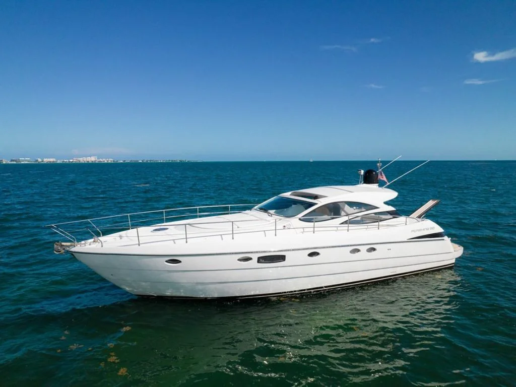 Luxury 50ft Pershing yacht charter cruising sunny Miami waters with city skyline backdrop.