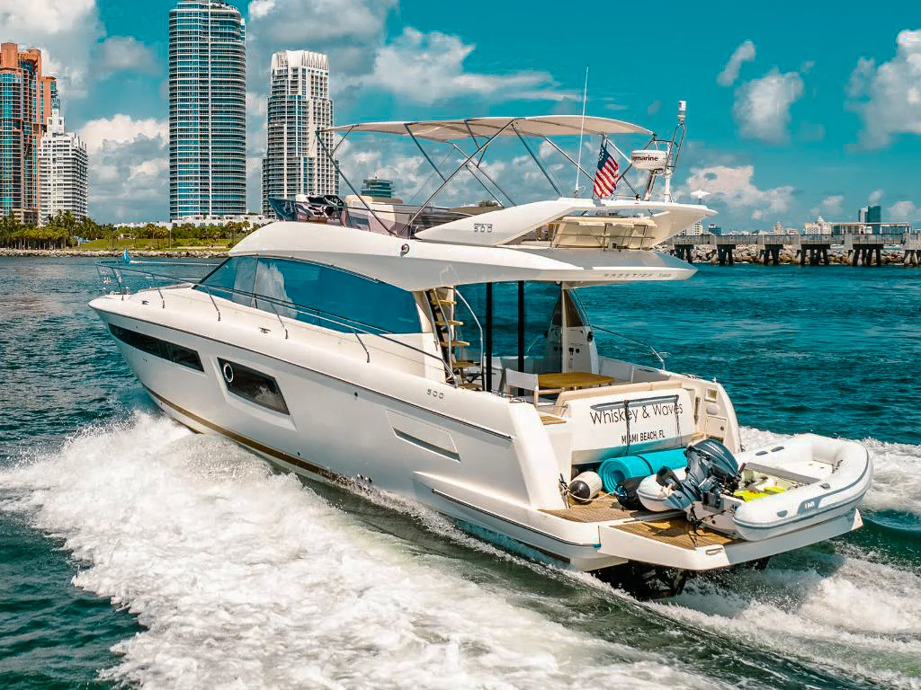 Luxurious 52ft Prestige Fly yacht cruising in the vibrant blue waters of Miami.