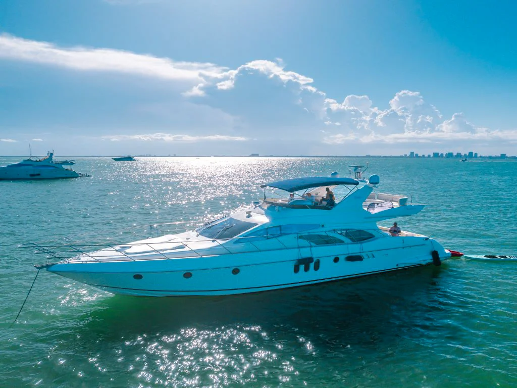 A luxury white motor yacht cruising through the turquoise waters of South Florida during a sunny spring day