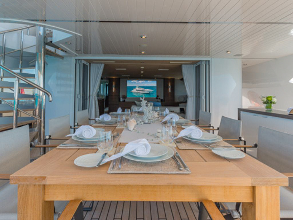 Guests on hammocks over clear blue water next to the 157 Oceanfast yacht