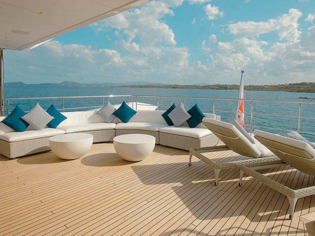 People relaxing on the private beach with a yacht in the background