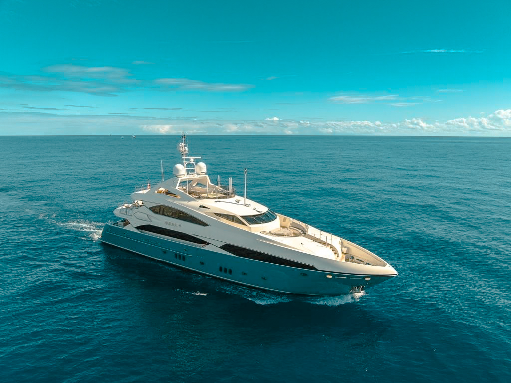 Couple enjoying a luxury yacht charter in a Mediterranean cove with a chef preparing breakfast.