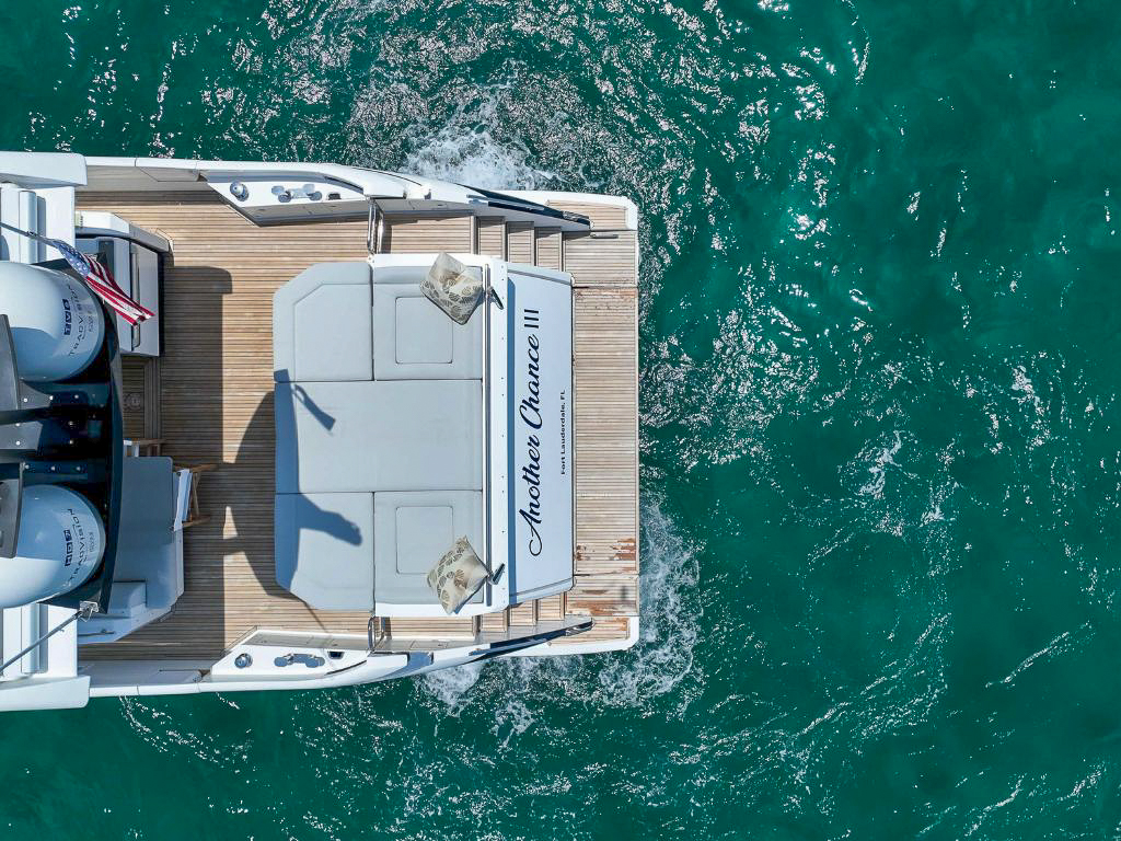 A wide view of the 70 Azimut IV's front deck with lounge seating and Miami skyline in the background